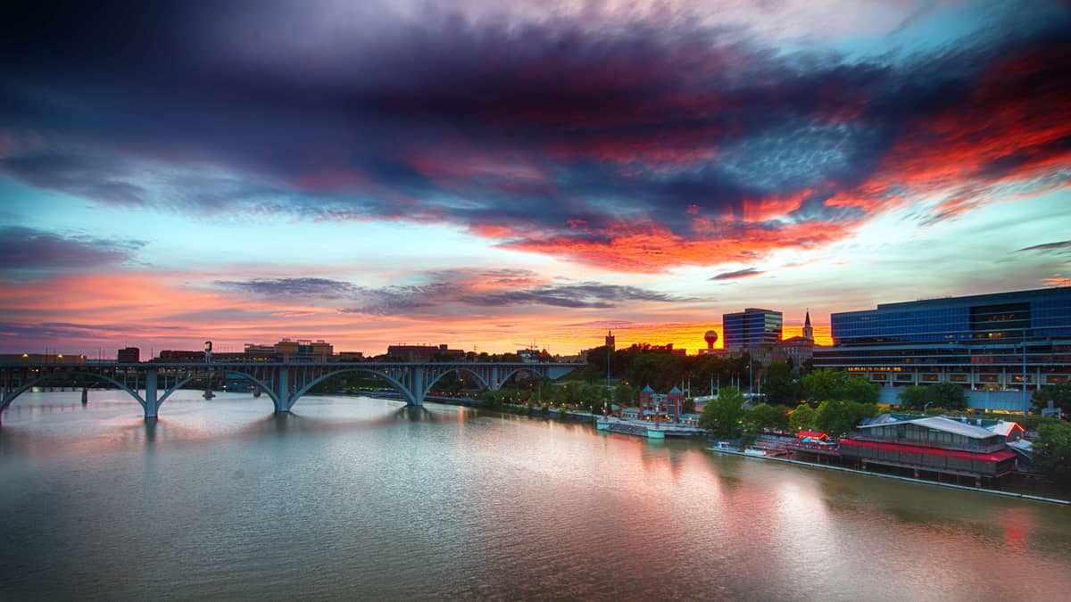 The Knoxville, Tennessee riverfront at sunset, with the Tennessee River, the Henley Street Bridge, and the Sunsphere